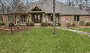 A brick home in the middle of a wooded area.