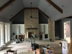 A living room with a stone fireplace and wood beams.