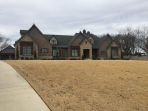 The front of a brick home with grass in the front yard.