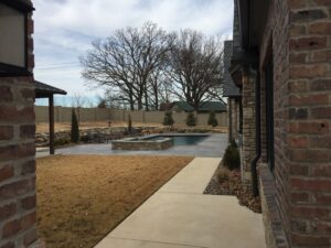 A backyard with a brick patio and a pool.