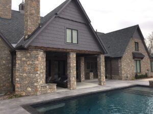 A house with a pool and stone siding.