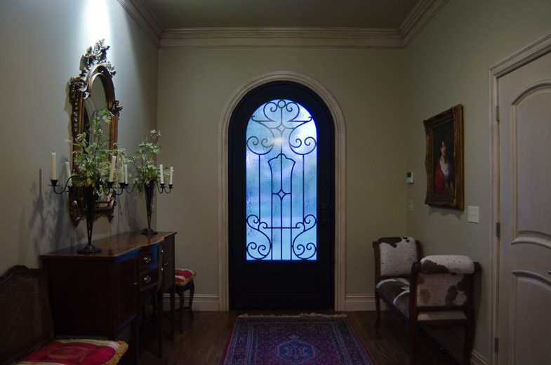 A hallway with an ornate door and a rug.