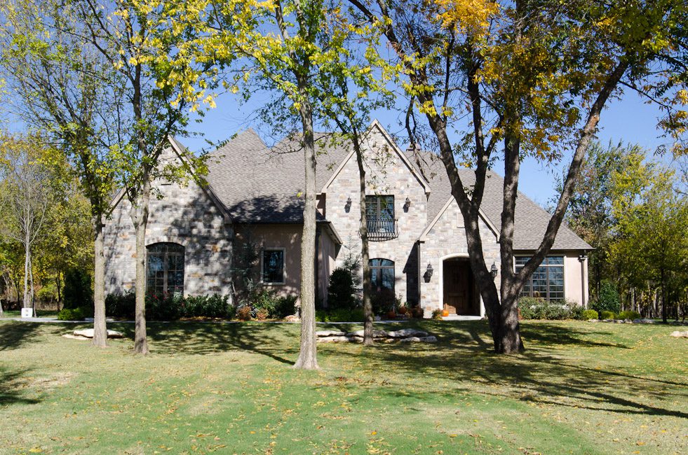 A large stone house in the middle of a grassy yard.