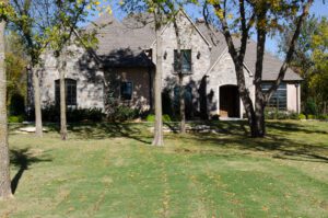 A large stone house in the middle of a grassy yard.