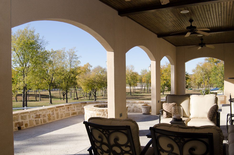 A covered patio with chairs and a fire pit.