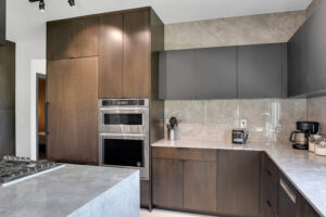 A modern kitchen with wooden cabinets and marble counter tops.