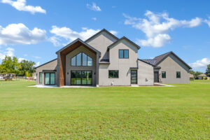 A modern home in the middle of a grassy field.