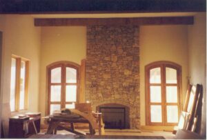 A stone fireplace in a room that is under construction.