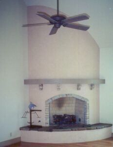 A living room with a fireplace and a ceiling fan.